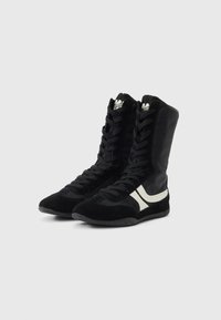 Černé vysoké tenisky kombinující semiš a síťovinu, s bílým pruhem jako akcentem a texturovanou podrážkou. Šněrování s polstrovaným lemem.