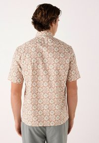 Kortærmet skjorte med et beige blomstermotiv og grønne og brune accenter. Krave-design med en afslappet pasform og glat tekstur.