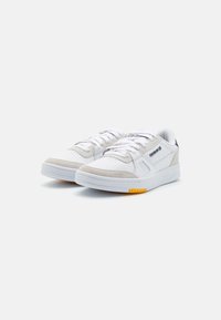 Sneakers bianchi con dettagli in camoscio grigio, punta rotonda, suola piatta in gomma e lacci bianchi. Dettaglio giallo sulla suola per una maggiore aderenza.