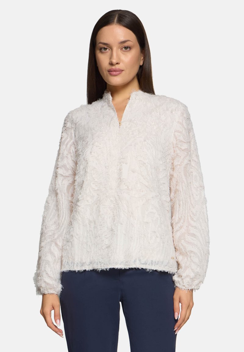 Weißer strukturierter Pullover mit hohem Kragen, langen Ärmeln und einem weichen, flauschigen Finish. Mit kunstvollen Mustern, die in den Stoff eingewebt sind.