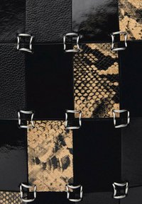 Čierno-hnedá patchwork kožená taška, ktorá obsahuje lesklé a textúrované panely zabezpečené striebornými kovovými doplnkami.