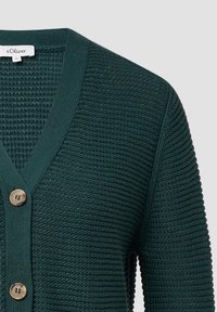 Dunkelgrüner Cardigan mit strukturiertem Strickmuster, V-Ausschnitt und drei Holzknöpfen. Verfügt über lange Ärmel und Rippendetails entlang der Kanten.