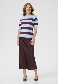Top a strisce in blu chiaro e bordeaux, con maniche corte; abbinato a una gonna lunga bordeaux e tacchi a punta. Texture liscia.