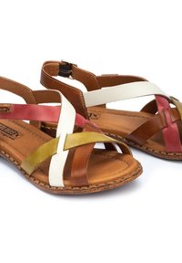 Bruna lädersandaler med korsade remmar i rött, vitt och grönt, med en platt sula och spänne för en säker passform.