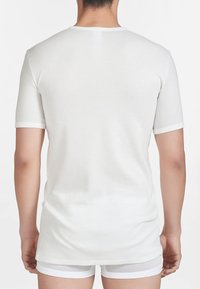 T-shirt bianco a maniche corte con scollatura rotonda e rifiniture a contrasto lungo le maniche e l'orlo. Tessuto liscio con un leggero allungamento.