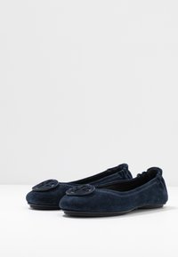 Ballerines en daim bleu marine avec un bout rond, accent de bouton noir décoratif et détails cousus le long du bord. Construction douce et flexible.