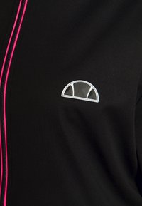 Zwarte jas met een roze rits en een klein wit logo met een halfcirkelontwerp. Gladde textuur, minimalistische stijl.