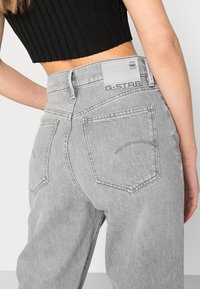 Šedé džíny z denimu s vysokým pasem, s G-Star štítkem na zadní straně. Tkanina má jemnou texturu a strukturovaný tvar, s decentním prošíváním.