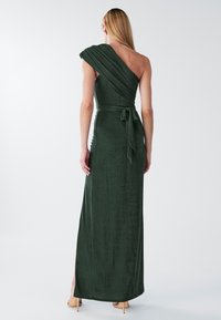 Zelené jedno-ramenné šaty po zem z textúrovaného materiálu, s bočným rozparkom a zaväzovaným pásom ako akcentom. Hladký povrch.