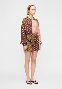 Πολύχρωμο φόρεμα πουκάμισο με μείγμα σχεδίων πεϊσλεϊ και γεωμετρικών μοτίβων, μακριά μανίκια, μπροστινό κλείσιμο με κουμπιά και ελαστική μέση.