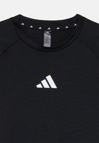 T-shirt de sport noir avec un logo Adidas blanc. Comprend un col rond et un col intérieur à motif contrasté.