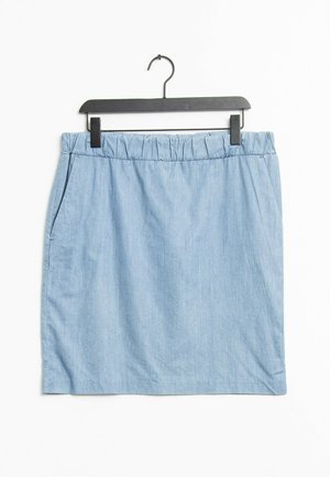 Falda vaquera azul claro con cinturilla elástica y bolsillos laterales, colgada en una percha de plástico negra sobre un fondo blanco.