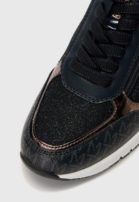 Baskets bleu marine avec un dessus en paillettes noires texturées, accents brillants et détails imprimés. Dotées de lacets noirs et d'une semelle blanche.