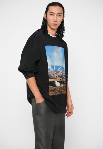 Felpa nera oversize con una grafica colorata di natura, raffigurante montagne e una tenda. Tessuto morbido, vestibilità rilassata e polsini a coste.