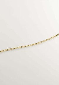 Cadena de metal dorado con enlaces ovalados entrelazados, textura suave y un acabado uniforme, que se extiende diagonalmente sobre un fondo claro.