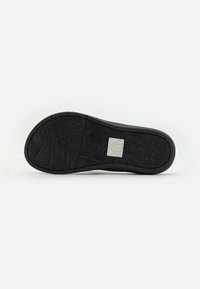Semelle de chaussure en caoutchouc noir avec un motif texturé comportant des motifs de feuilles. Boîte de logo centrée avec des lettres en relief. Bords arrondis pour une meilleure adhérence.