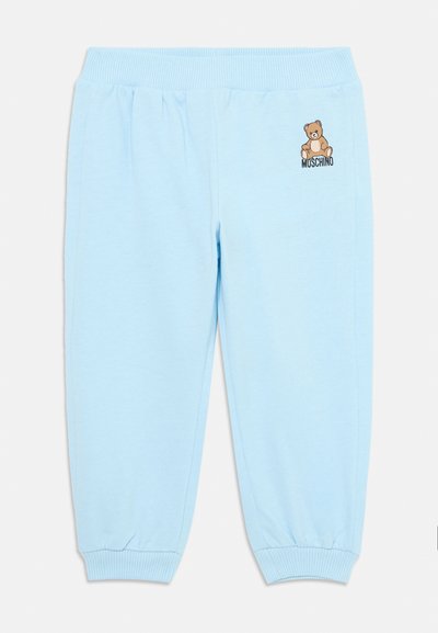 Calças de moletão azul claro feitas de um tecido macio, com uma cintura e punhos elásticos, apresentando uma pequena grafia de um urso castanho e o logótipo "Moschino".