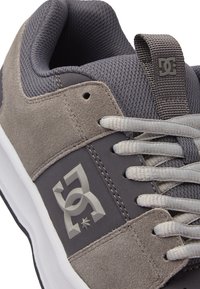 Szare sneakersy z mieszanką materiałów zamszowych i siateczkowych, z białymi sznurówkami, logo po boku oraz wyściełanym kołnierzem dla komfortu.