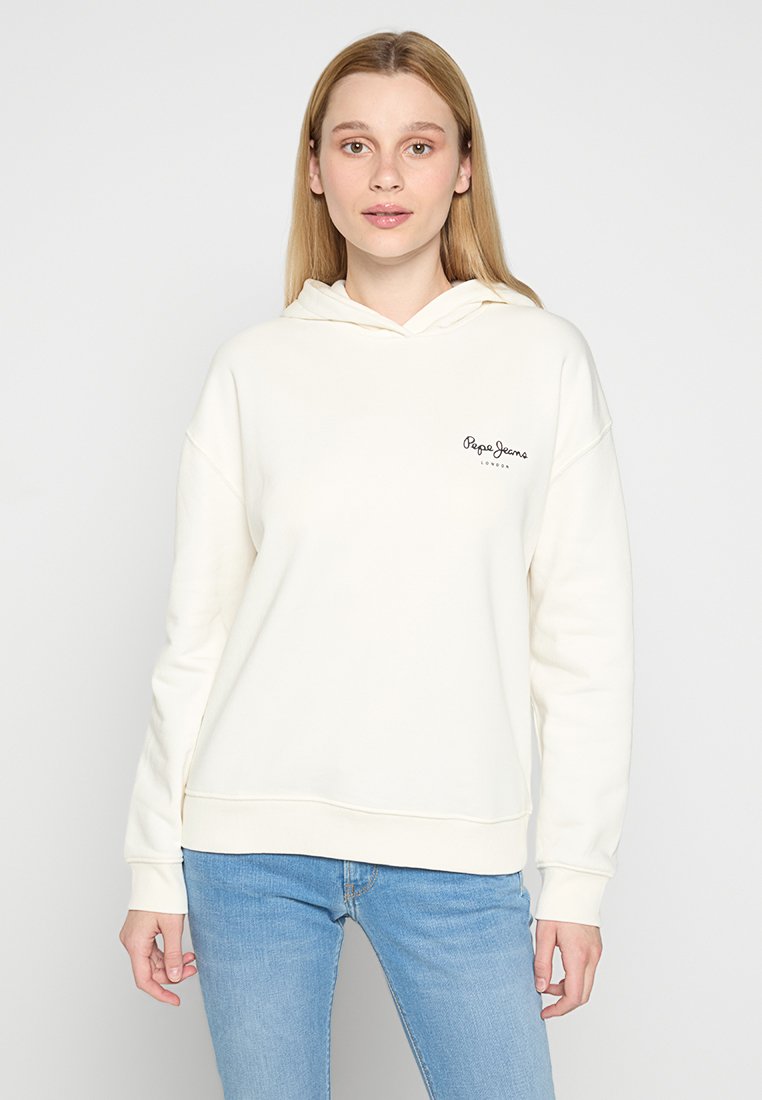 Sudadera color crema hecha de una tela suave, con un bolsillo tipo canguro en la parte delantera y un pequeño logo negro en el lado izquierdo del pecho. Corte casual con capucha.