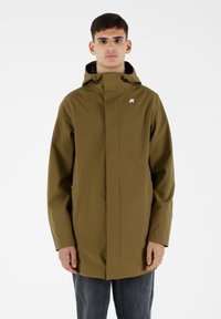 Giacca impermeabile verde oliva con colletto alto, due tasche laterali e un piccolo logo sul petto. Progettata con un taglio dritto.