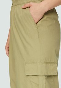 Lichte olijfgroene cargobroek met een elastische tailleband, zijzakken en een klepzak op de dij, gemaakt van een zachte, gestructureerde stof.