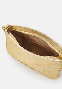 Goldene, mit Pailletten verzierte Clutch mit goldenen Reißverschluss und Innentasche, die mit "LOVE MOSCHINO" beschriftet ist, vor weißem Hintergrund.