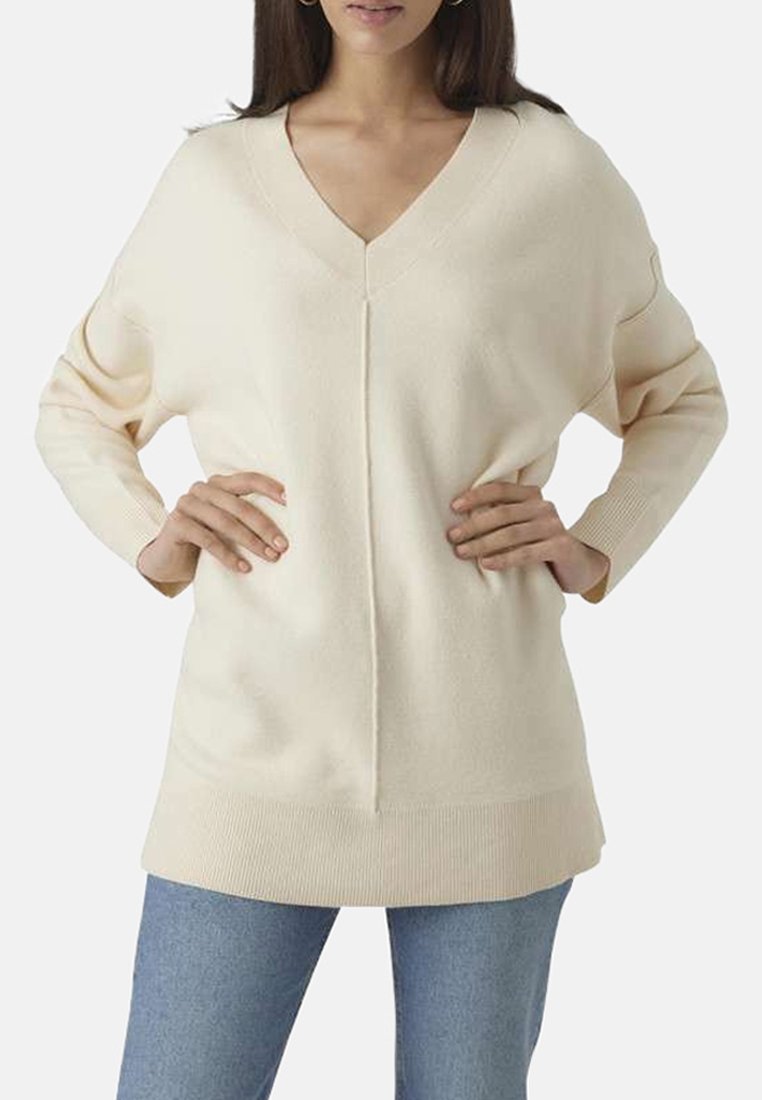Pull V beige clair à col en V avec des manches longues, des poignets et un ourlet côtelés, présentant un détail de couture central et une coupe décontractée.