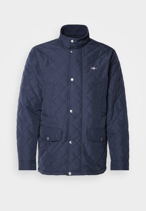 Námořnická prošívaná bunda s vysokým límcem, dvěma bočními kapsami, zapínáním na patentky a malým logem na levé horní části hrudi.