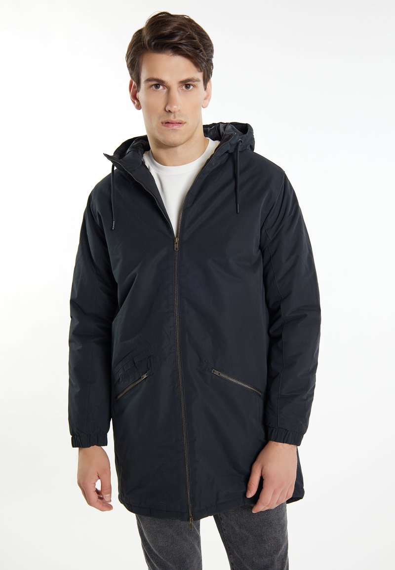 Giacca nera con cappuccio, con zip anteriore, polsini elasticizzati, due tasche laterali e orlo leggermente più lungo. Realizzata in tessuto leggero e liscio.