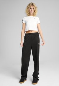 Vit kortärmad t-shirt med svart halsringning; svarta sweatpants med vita sidostreck och elastisk linning; svarta sneakers med gummisula.