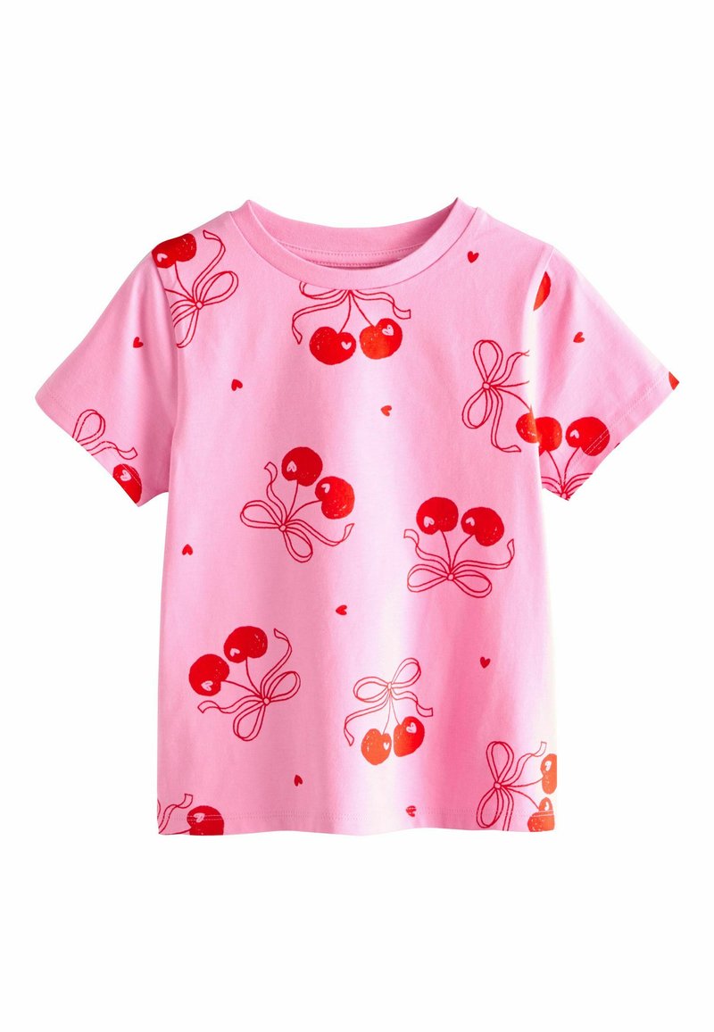 Camiseta de algodón rosa con un patrón repetido de cerezas y lazos rojos. Mangas cortas y cuello redondo. Textura suave, ajuste informal.