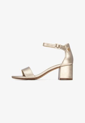 Sandalia metálica dorada con tacón ancho, puntera abierta, una sola tira frontal y correa ajustable en el tobillo con detalle de hebilla.