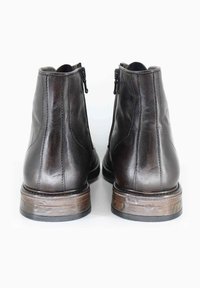 Stivali alla caviglia in pelle marrone con chiusura a zip e finitura testurizzata; suola in gomma con rifinitura in legno e dettagli di cucitura.