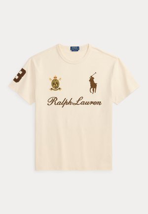 T-shirt crème Ralph Lauren avec logo joueur de polo marron, numéro 3 sur la manche droite, et emblème de blason sur la poitrine gauche.