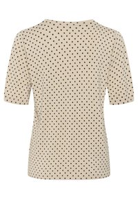 Haut beige à manches courtes avec des pois noirs, présentant un col rond et un design ajusté. Texture tricot lisse sur l'ensemble.