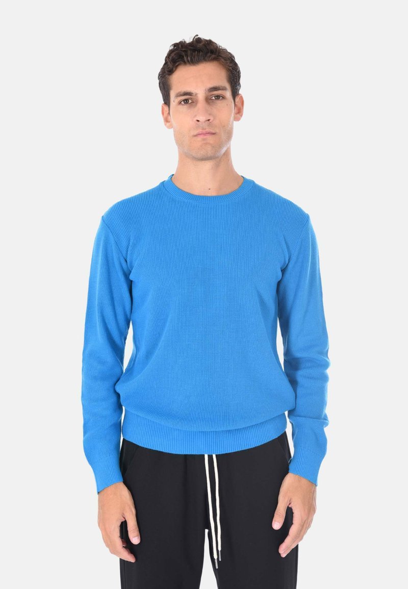 Maglione blu a maglia con texture a costine, scollo rotondo e maniche lunghe, abbinato a pantaloni neri con coulisse.