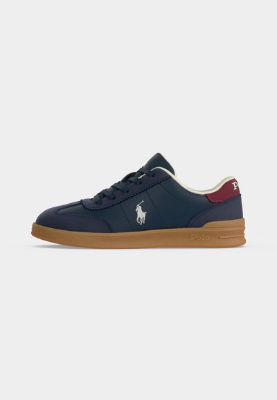 Ναυτικό μπλε χαμηλό sneaker με σόλα από καουτσούκ, λευκό λογότυπο Polo στο πλευρό και κόκκινο ταμπελάκι στη φτέρνα με λευκό κείμενο Polo, με μαύρα κορδόνια και λευκή επένδυση στο εσωτερικό.