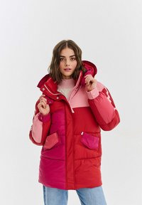 Představujeme zateplenou bundu s barevným blokem v odstínech červené a růžové, s kapucí, zipovým zapínáním a předními kapsami.