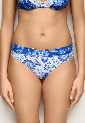 Kobieta nosząca niebiesko-białe kwiatowe dół bikini z pasującym składanym paskiem w talii oraz widoczną częścią pasującego topu.