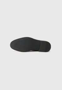Semelle de chaussure noire avec un motif de grip texturé, une forme arrondie et un bord lisse se transitionnant vers le talon. Matériau en caoutchouc durable.