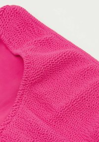 Un tissu rose vif présentant un motif texturé et ondulé. Un tissu lisse avec une qualité extensible près des bords, créant une forme courbée.