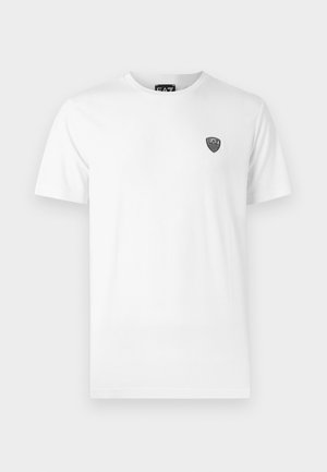 Bílý bavlněný tričko s krátkým rukávem, s malým černým logem v oblasti levého hrudníku. Klasický střih s kulatým výstřihem.