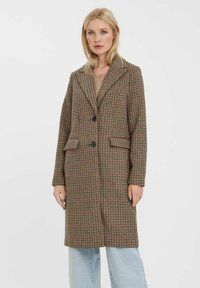 Hnědý kostkovaný kabát s klopou, dvěma předními kapsami a černými knoflíky. Vyroben z texturované tkaniny, s délkou do kolen.