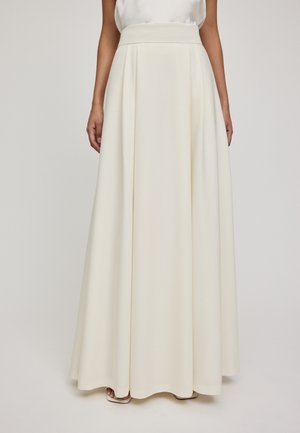 Jupe longue et fluide blanche avec une taille haute, fabriquée en tissu lisse. Elle présente des plis et un ourlet large, créant une silhouette élégante.