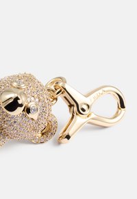 Portachiavi color oro caratterizzato da un design a forma di orso adornato con strass trasparenti. Include un gancio con la scritta "FURLA" incisa.