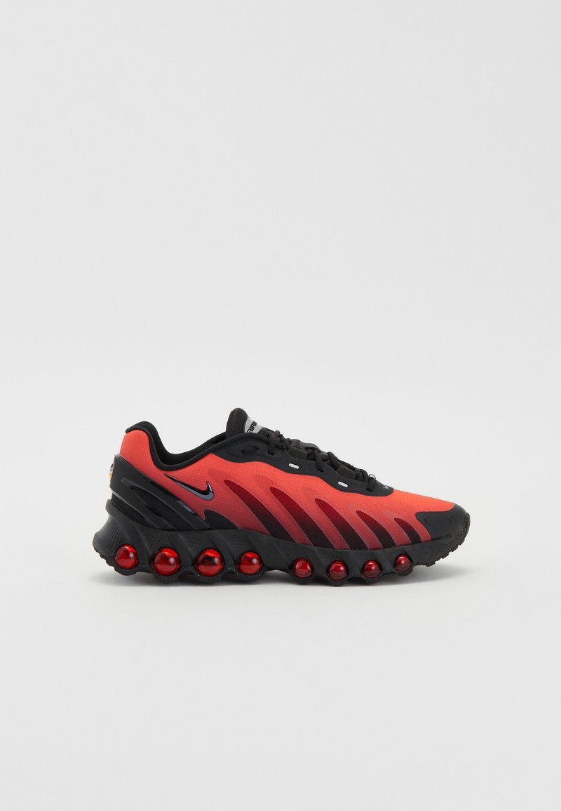 Zapatilla de running de Nike con un upper de malla en degradado rojo y negro, media suela negra texturizada y distintivas cápsulas de amortiguación rojas.