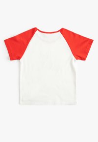 Camiseta de manga corta roja y blanca con textura acanalada. Mangas raglán rojas y cuello redondo, con una parte trasera lisa.