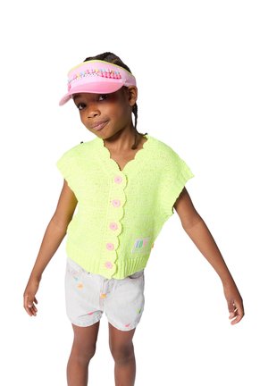 Veste en tricot vert néon avec bords festonnés et boutons roses, assortie à un short gris clair avec des motifs colorés. Visière rose avec des accents.