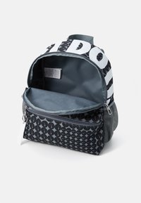 Μαύρο και γκρι σακίδιο πλάτης με κυκλικό μοτίβο και έντονα λευκά γράμματα. Διαθέτει ανοιχτή κύρια θήκη και κλειστή μπροστινή τσέπη με φερμουάρ.