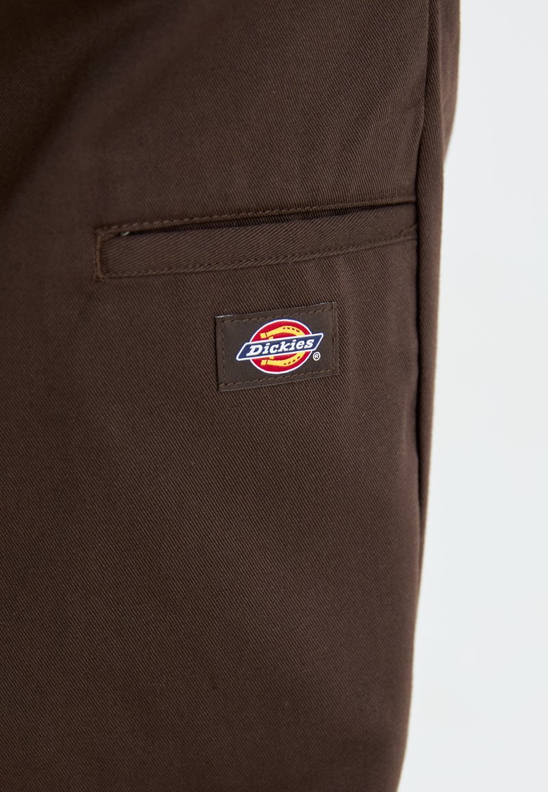 Braune Arbeitsmesse mit einem kleinen gewebten "Dickies"-Logo-Patch. Verfügt über eine Seitentasche mit einer sauberen, robusten Verarbeitung.